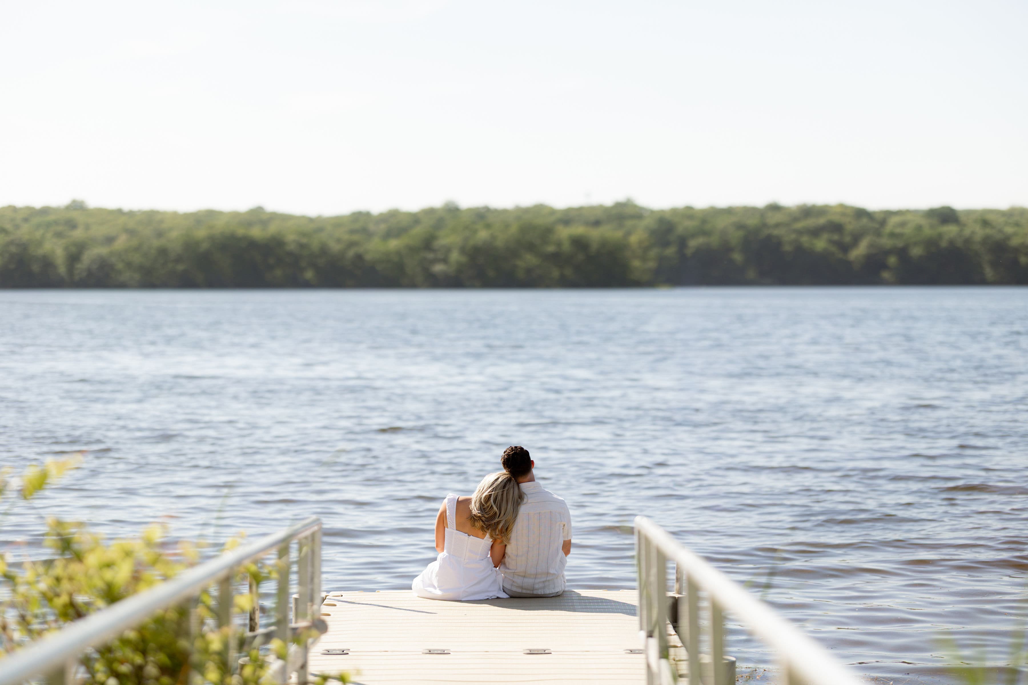 Jess and Allison sitting together on a dock overlooking the lake